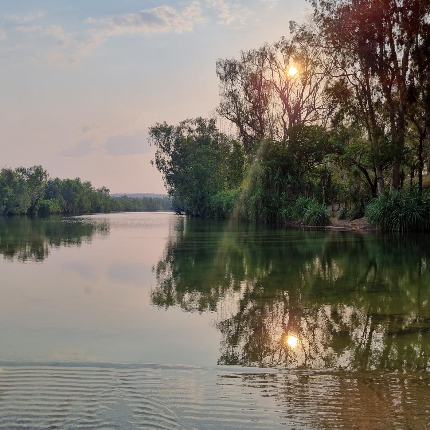Roper Bar Crossing (Lauri Turner | ©AAPA) Still river reflecting trees with sun setting