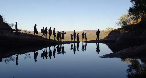 Silhouetted people standing on the edge of the Gunlom Falls top pool